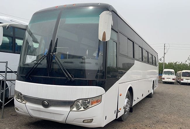 White 60-seat touring coach, front three-quarter view