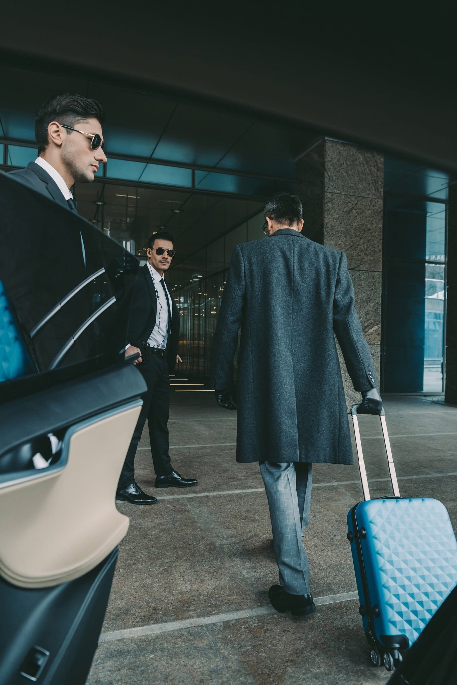 Chauffeur holding the car door for a guest arriving with luggage